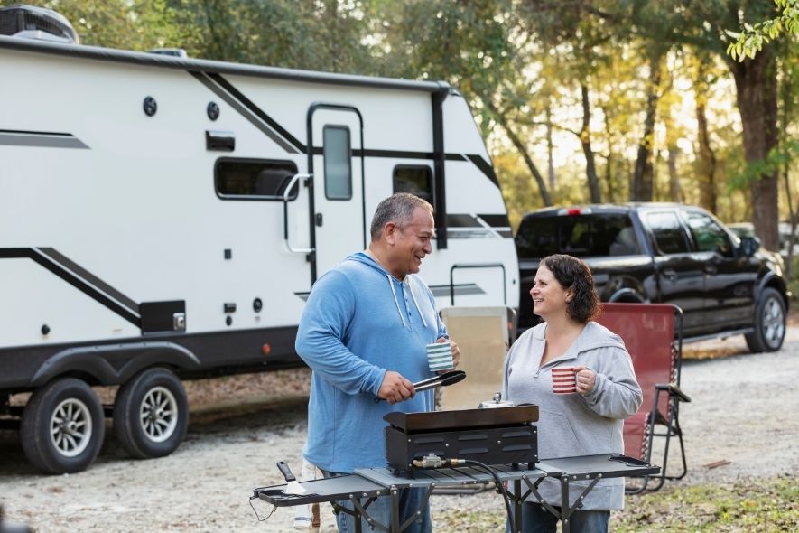 TWO PEOPLE CAMPING OUTSIDE AN RV