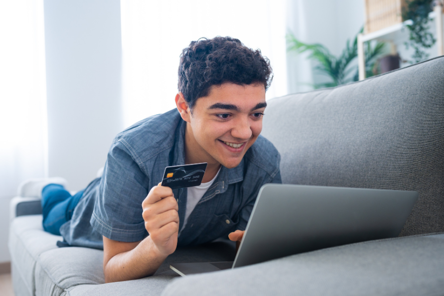 young man holding credit card on couch